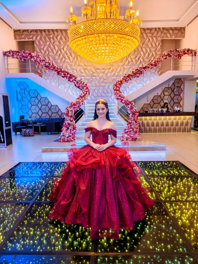 Debutante de vestido vermelho no salão do Espaço Montello com escadaria florida